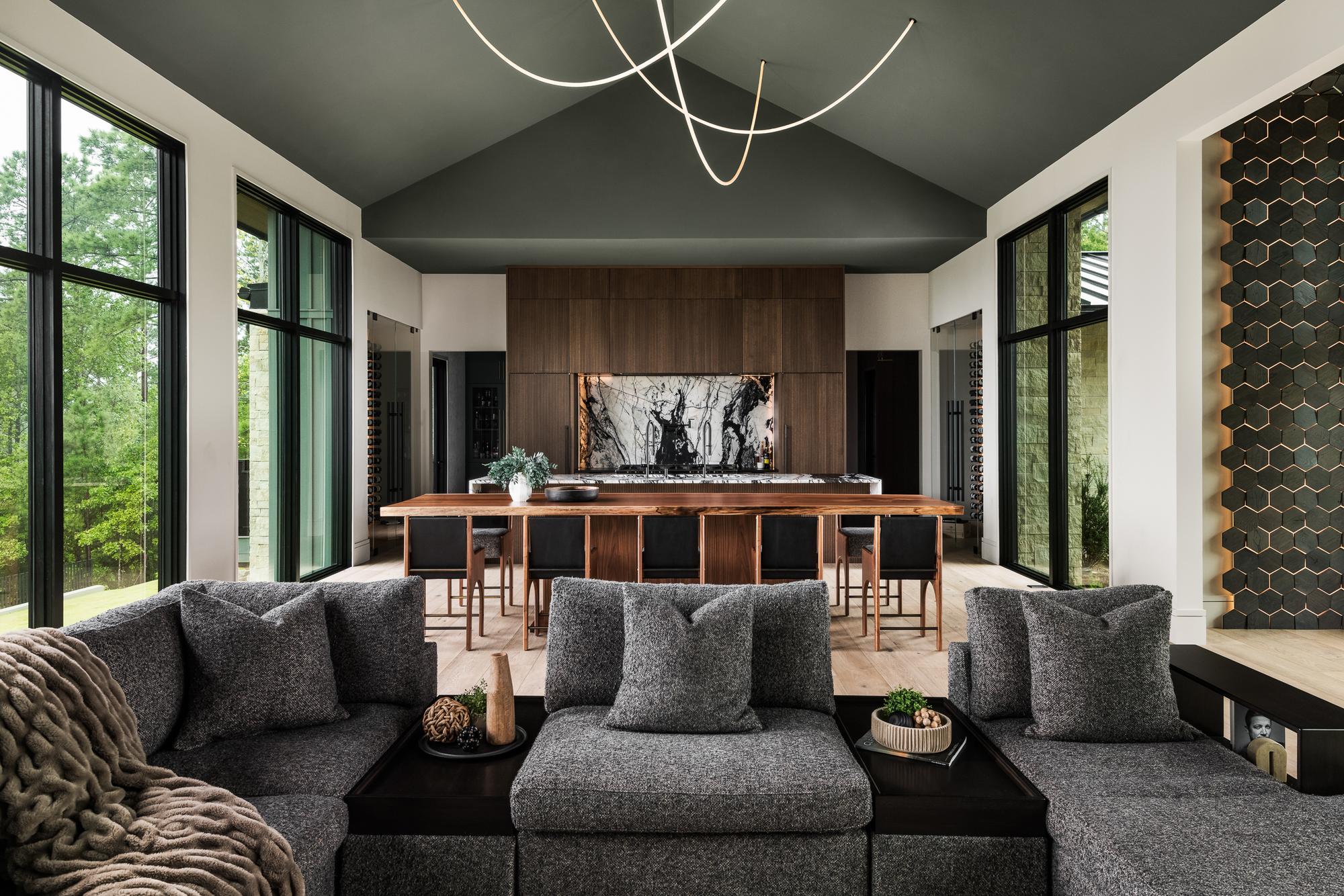 Modern open-plan great room with walnut island, marble backsplash, and floor-to-ceiling windows — Mac & Morgan Interiors, Lake Keowee