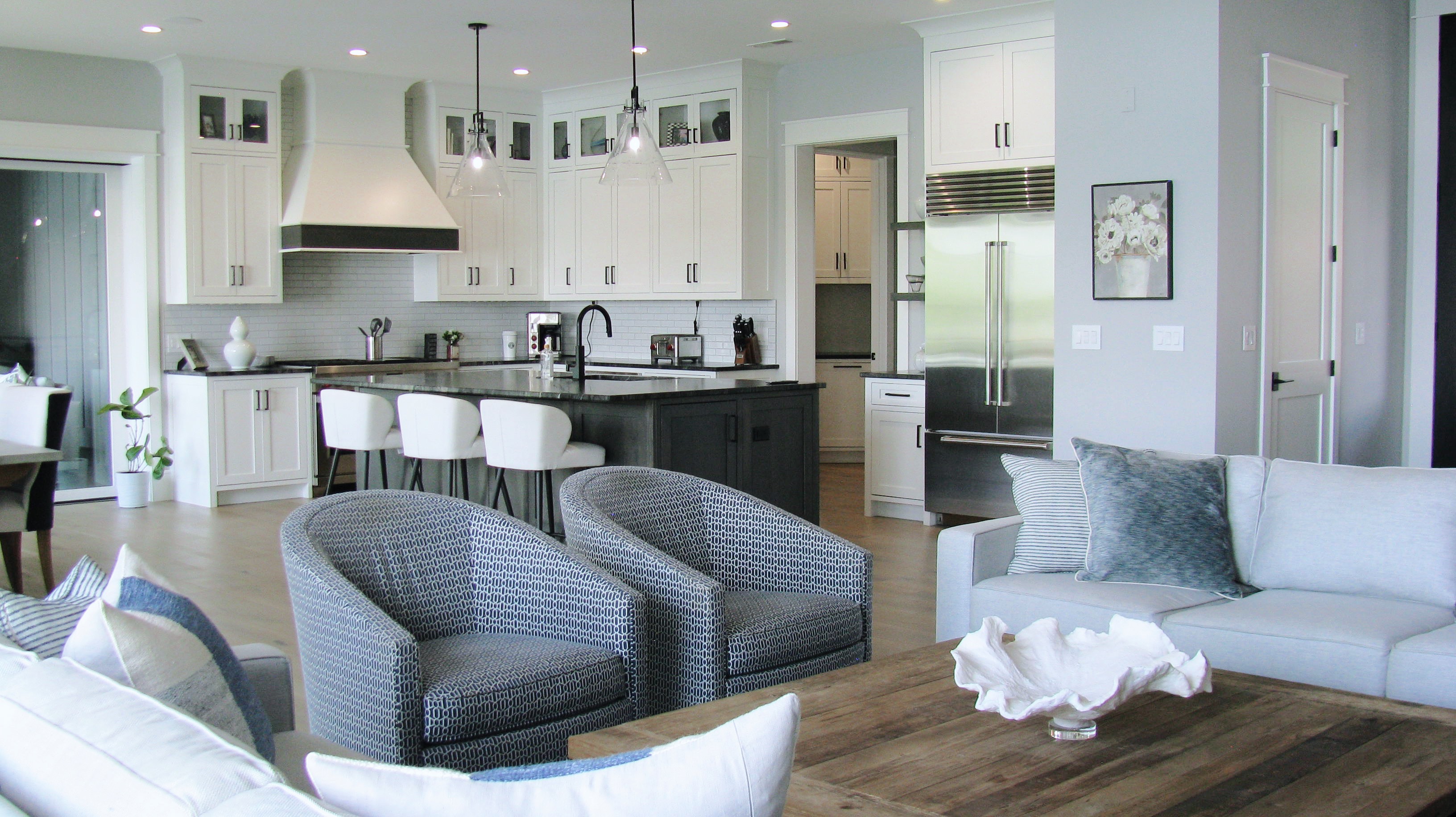 Open-concept kitchen and living room with white cabinetry, dark island, and custom furniture selections — Mac & Morgan Interiors, Seneca SC