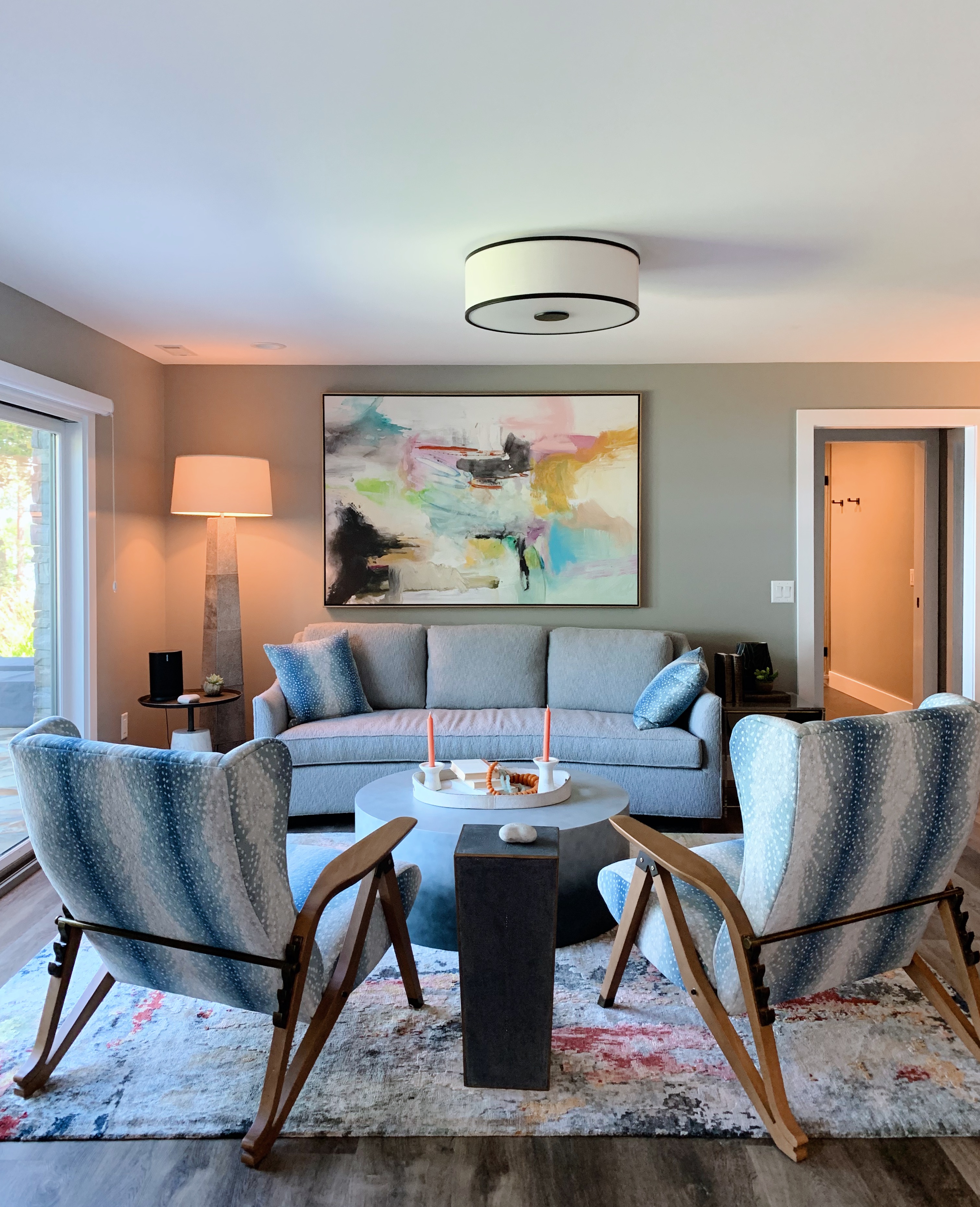 Living room with blue-grey sofa, patterned accent chairs, and large abstract canvas — residential interior design by Mac & Morgan Interiors